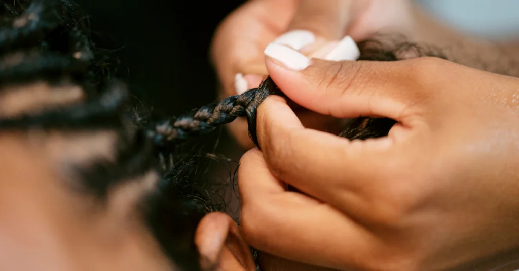 Woman applying anti-dandruff spray to scalp through braided hair