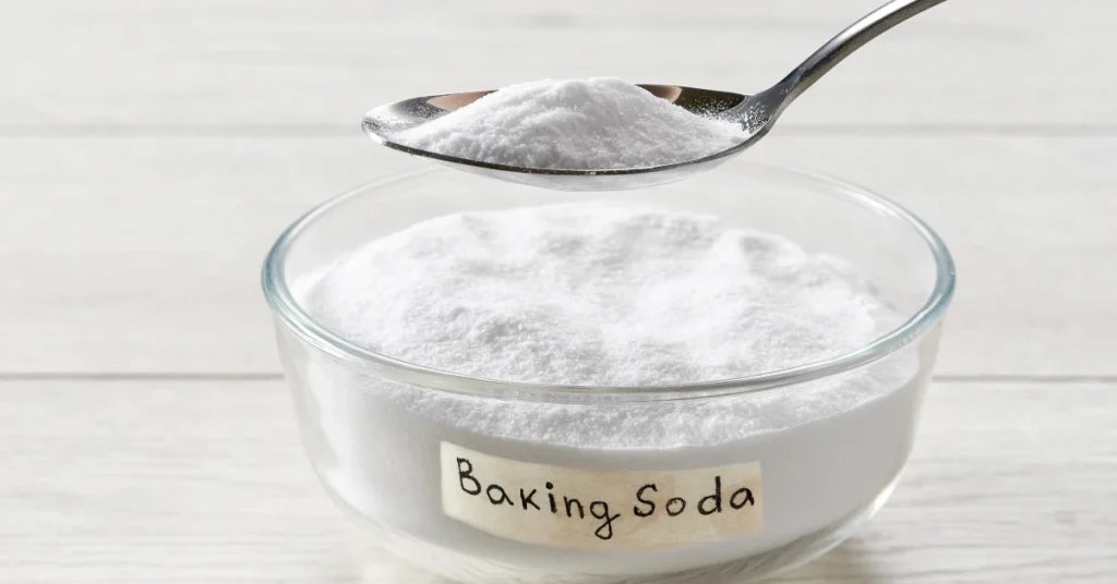 Spoonful of baking soda over a glass bowl of baking soda