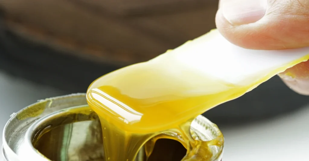 Hand in yellow glove wiping sticky glue residue off a metal object