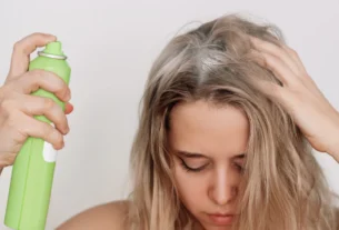 Woman spraying dry shampoo on roots at home