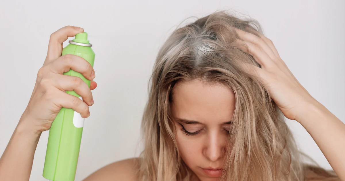 Woman spraying dry shampoo on roots at home