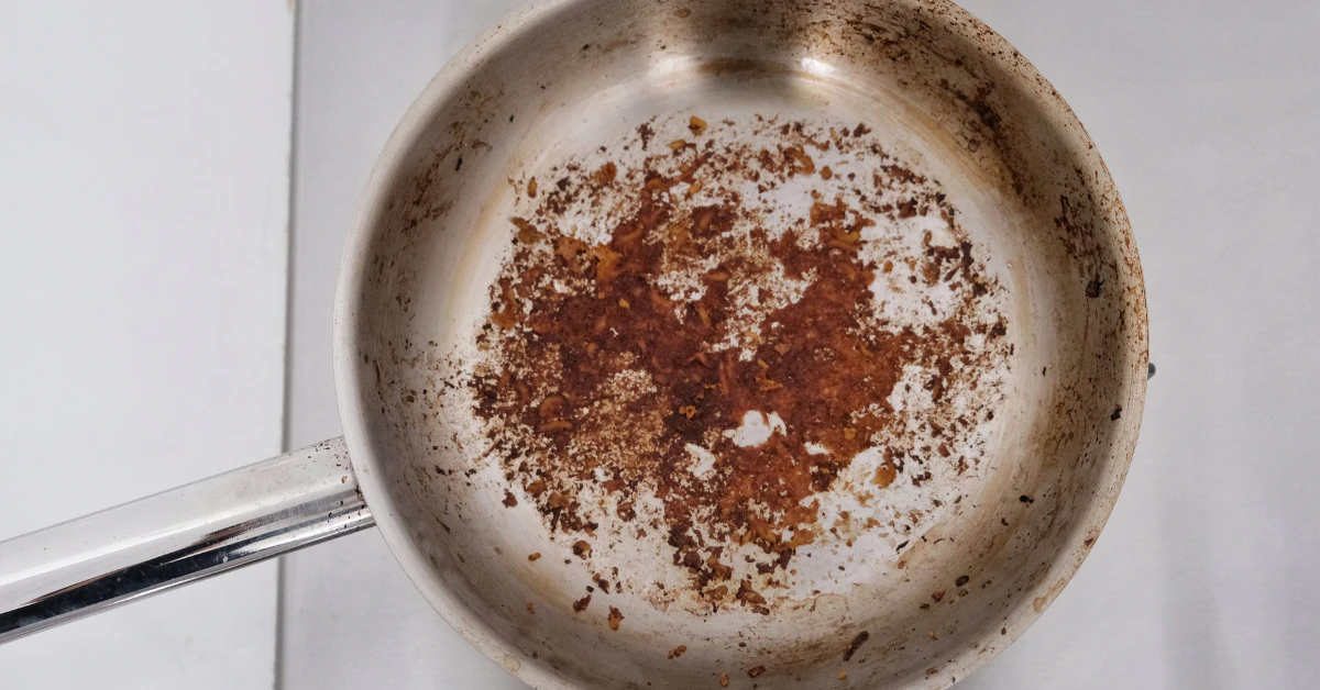 Burnt food residue stuck on the inside of a stainless steel pan