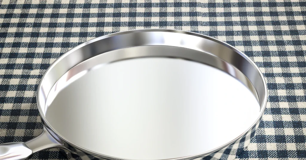 Clean empty stainless steel pan on a checkered cloth after removing burnt residue