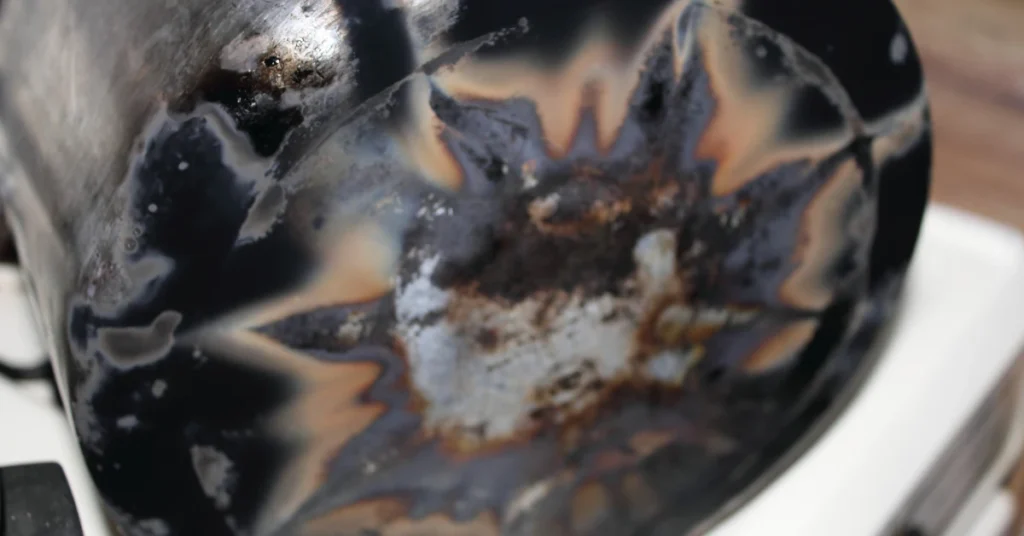Scorched and discolored outer bottom of a burnt pan on a stovetop