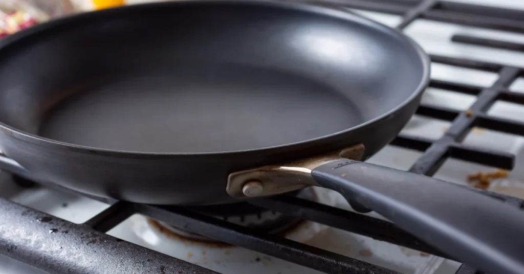 Black non-stick frying pan on a stovetop ready for gentle cleaning
