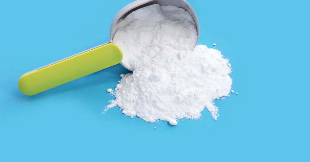 Scoop of white baking soda powder on a blue background
