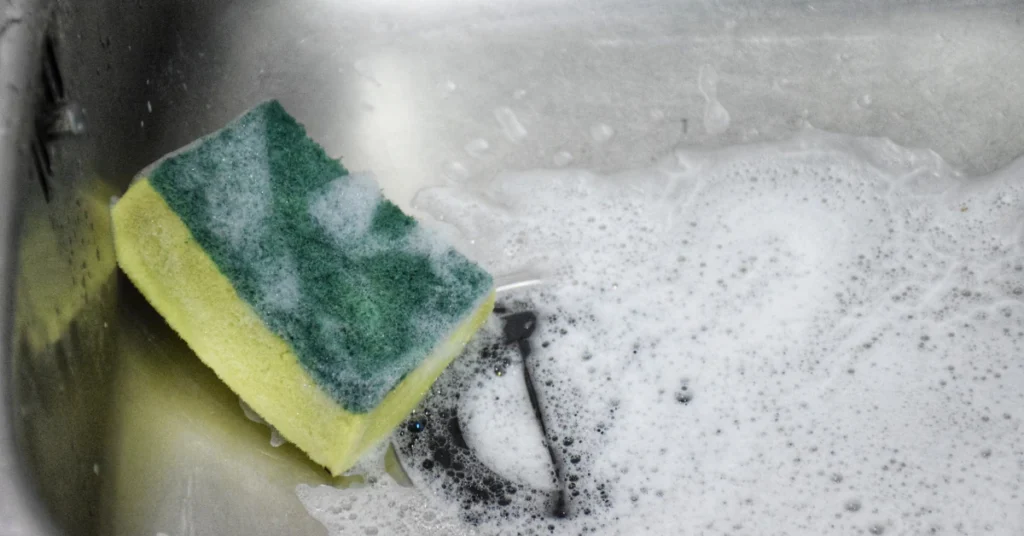 Yellow and green scrub sponge resting in white cleaning powder