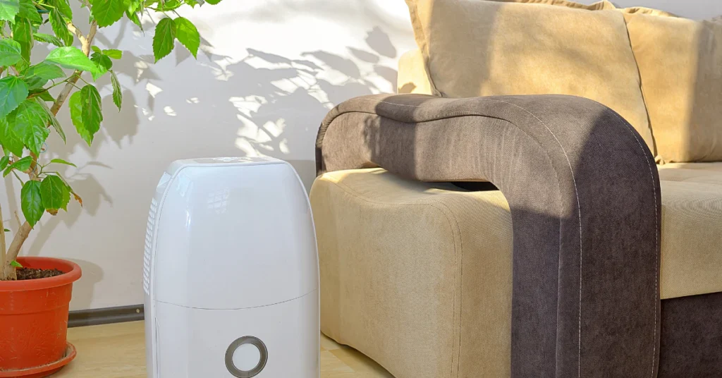 White dehumidifier running in a living room next to a sofa