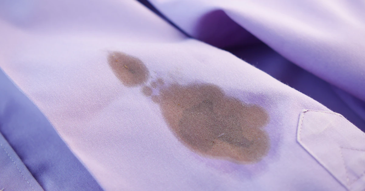 Oil stain on a light purple shirt, showing a grease mark that needs to be removed from clothes