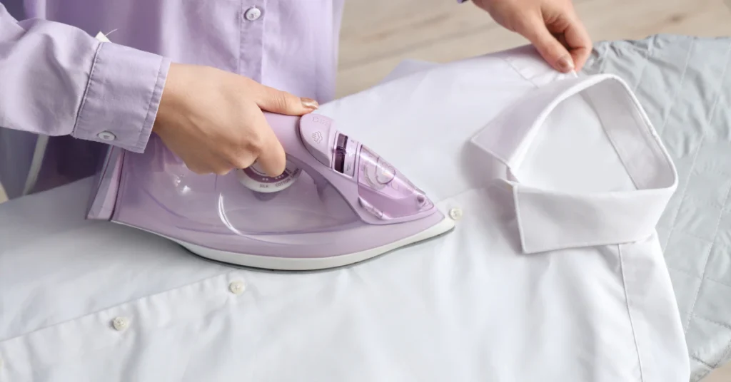 Person ironing a stained piece of clothing on an ironing board using an iron