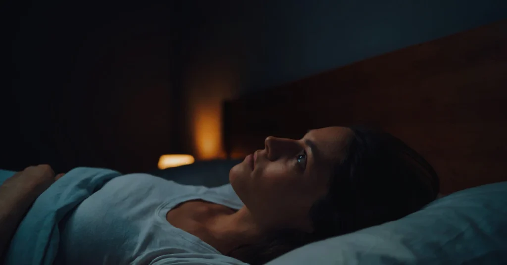 Person lying awake in a dark bedroom at night