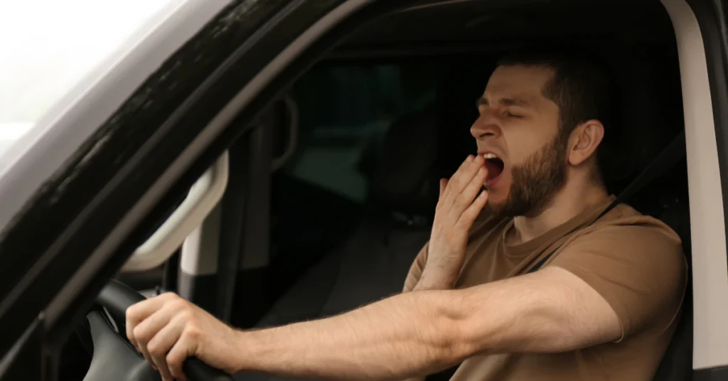 Drowsy driver yawning behind the wheel of a car