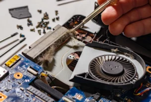 Technician's hand repairing the cooling fan inside an open laptop
