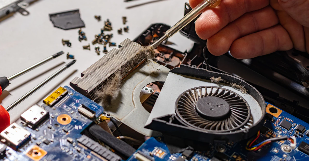 Technician's hand repairing the cooling fan inside an open laptop