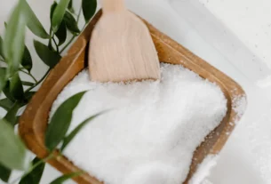 White crystalline salt powder in a wooden scoop, representing smelling salts made from ammonium carbonate