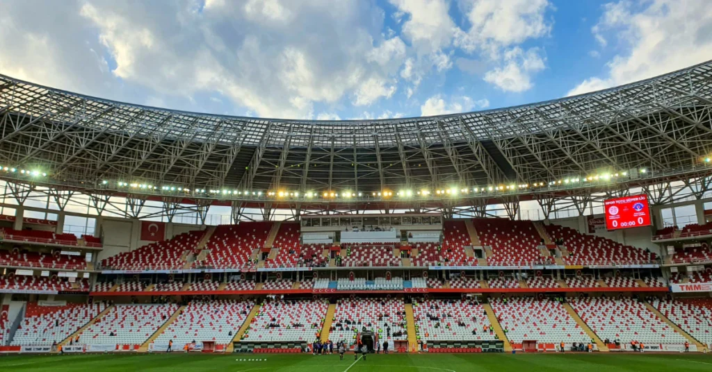 Empty football stadium with red seats under a blue sky, representing sports leagues and their rules